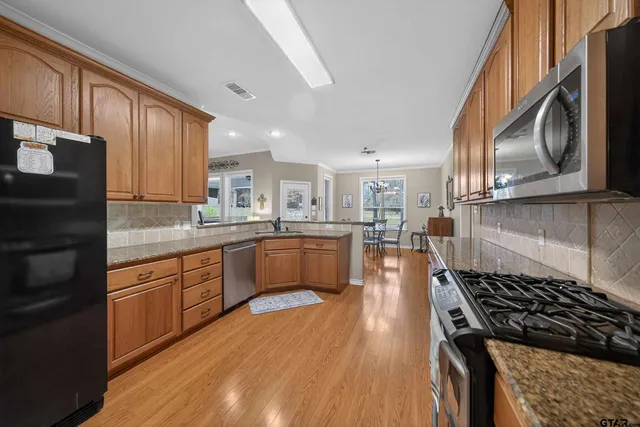 a kitchen with stainless steel appliances granite countertop a stove a sink dishwasher and a microwave oven with wooden floor