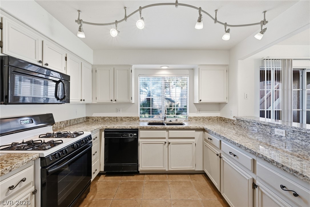 1851 Hillpointe Road, Unit 1311 Henderson, NV 89074 - Photo 13 of 47 Kitchen featuring black appliances, white cabinets, light tile patterned flooring, and light stone countertops
