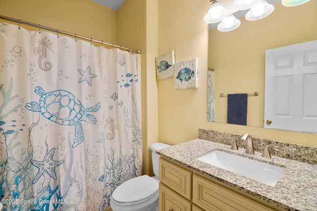 a bathroom with a granite countertop sink a toilet and a shower curtain