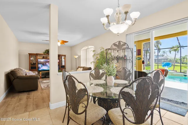 a view of a dining room with furniture a chandelier and large windows