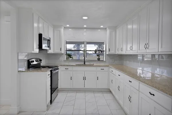 a kitchen with stainless steel appliances granite countertop a sink and dishwasher a stove top oven with white cabinets