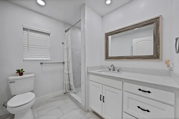a bathroom with a toilet sink vanity and mirror