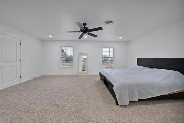 a spacious bedroom with a bed and a ceiling fan