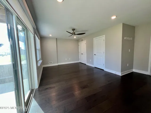 an empty room with wooden floor and a ceiling fan