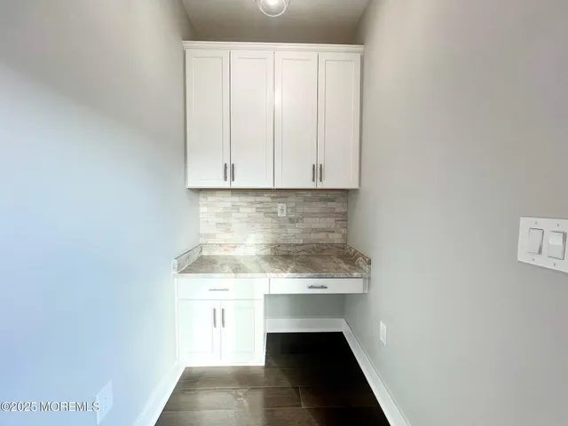 a view of kitchen with granite countertop white cabinets and sink