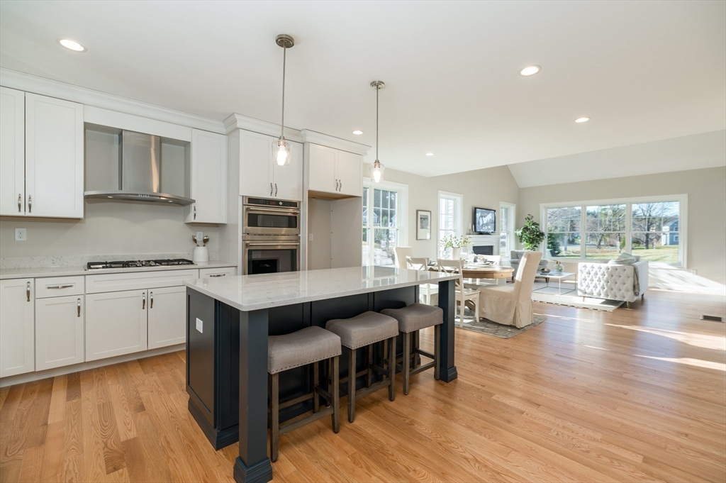 62 High Street, Unit LOT 1 Stoneham, MA 02180 - Photo 16 of 22 a kitchen with stainless steel appliances granite countertop a stove a sink dishwasher a dining table and chairs with wooden floor
