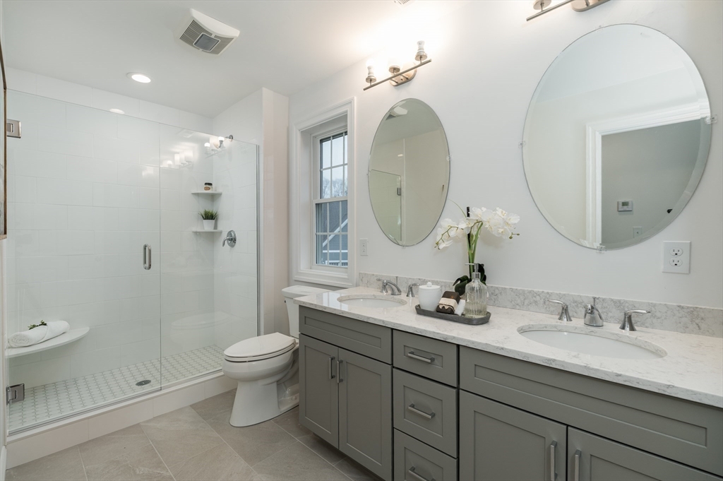 62 High Street, Unit LOT 1 Stoneham, MA 02180 - Photo 17 of 22 a bathroom with a toilet a double vanity sink and a mirror