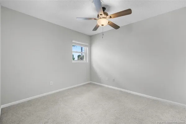 an empty room with a window and a fan