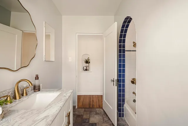 a bathroom with a granite countertop sink a mirror and shower