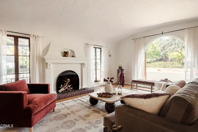 a living room with furniture a fireplace and large windows