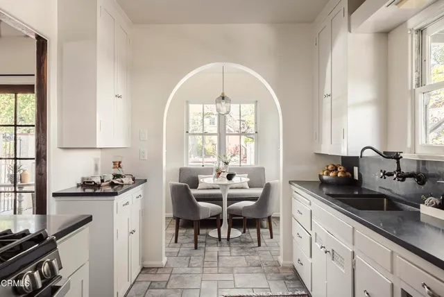 a kitchen with a sink a window and chairs