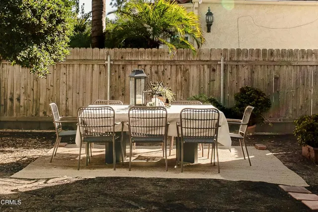 a patio with table and chairs and potted plants