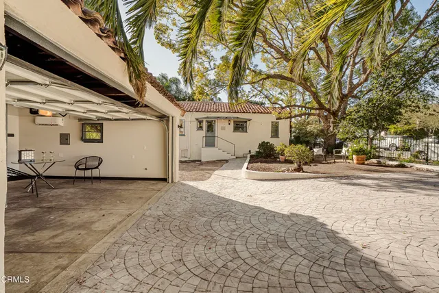 a view of a white house with a large tree