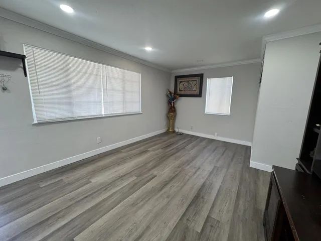 an empty room with wooden floor and windows