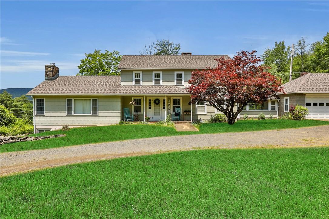 View of front facade featuring a garage, a front lawn, and covered porch