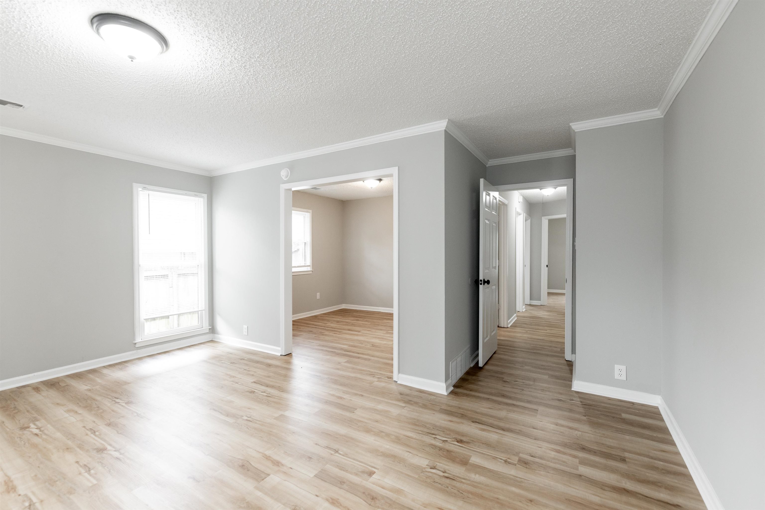 7421 Richmond Road Memphis, TN 38125 - Photo 22 of 39 Spacious interior showcasing wood-finish flooring, light gray wall tones, white trim, a flush mount ceiling light, and an open doorway to an additional room