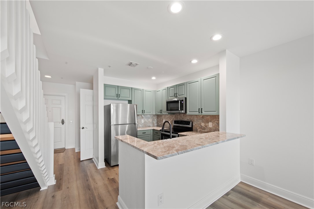 2745 First Street, Unit 113 Fort Myers, FL 33916 - Photo 7 of 35 a kitchen with stainless steel appliances a refrigerator a sink a stove top oven a wooden floor and cabinets