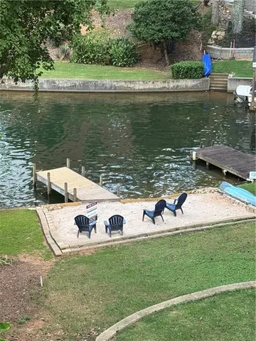 a view of a lake with a yard and a large tree