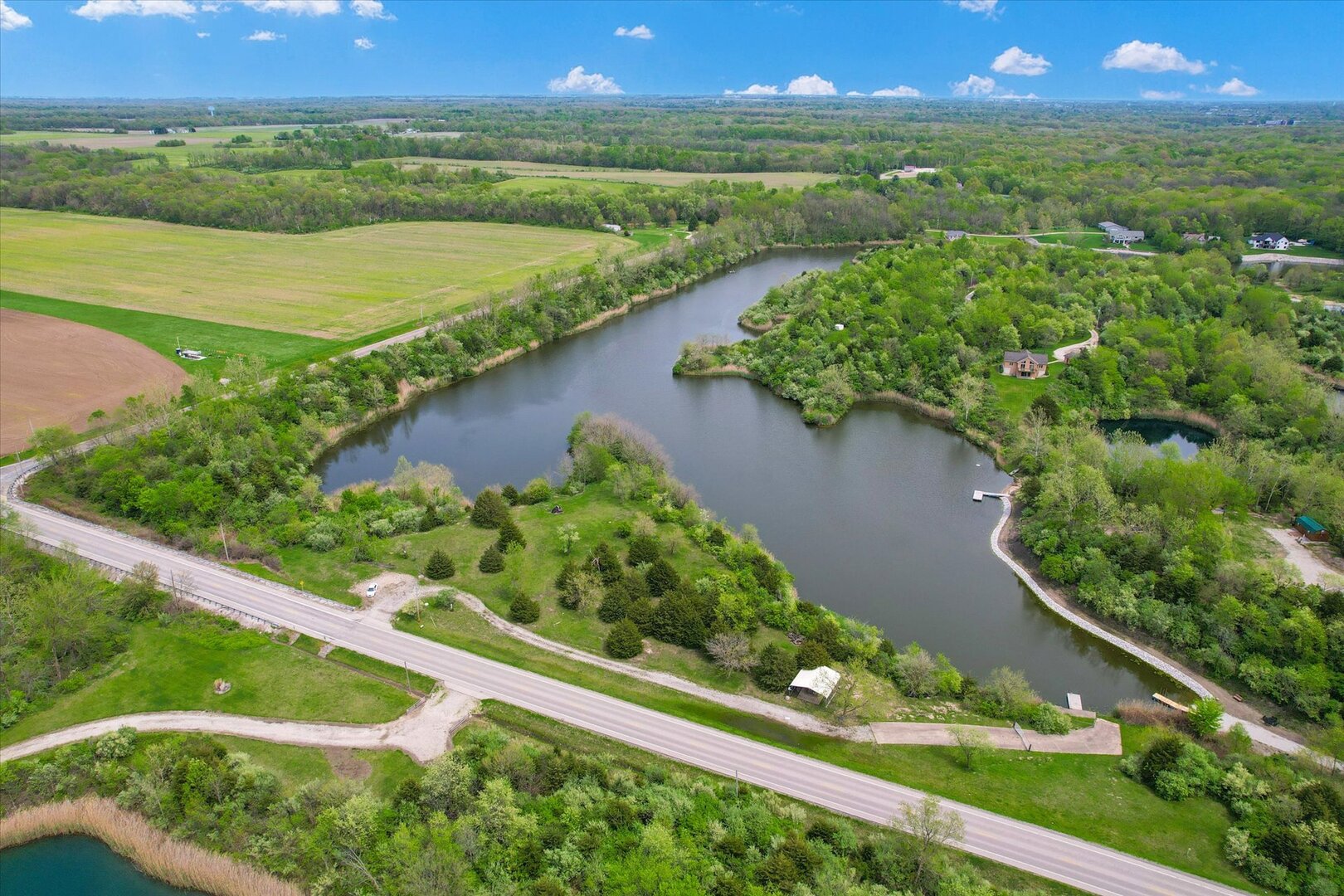 an aerial view of green landscape with trees houses and lake view