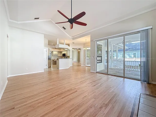 a view of a livingroom with wooden floor a ceiling fan and windows