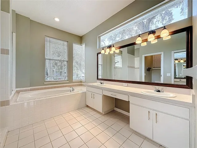 a bathroom with a sink mirror and a bathtub next to a window