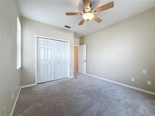 an empty room with closet and a ceiling fan