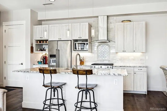 a kitchen with stainless steel appliances kitchen island wooden floors and white cabinets