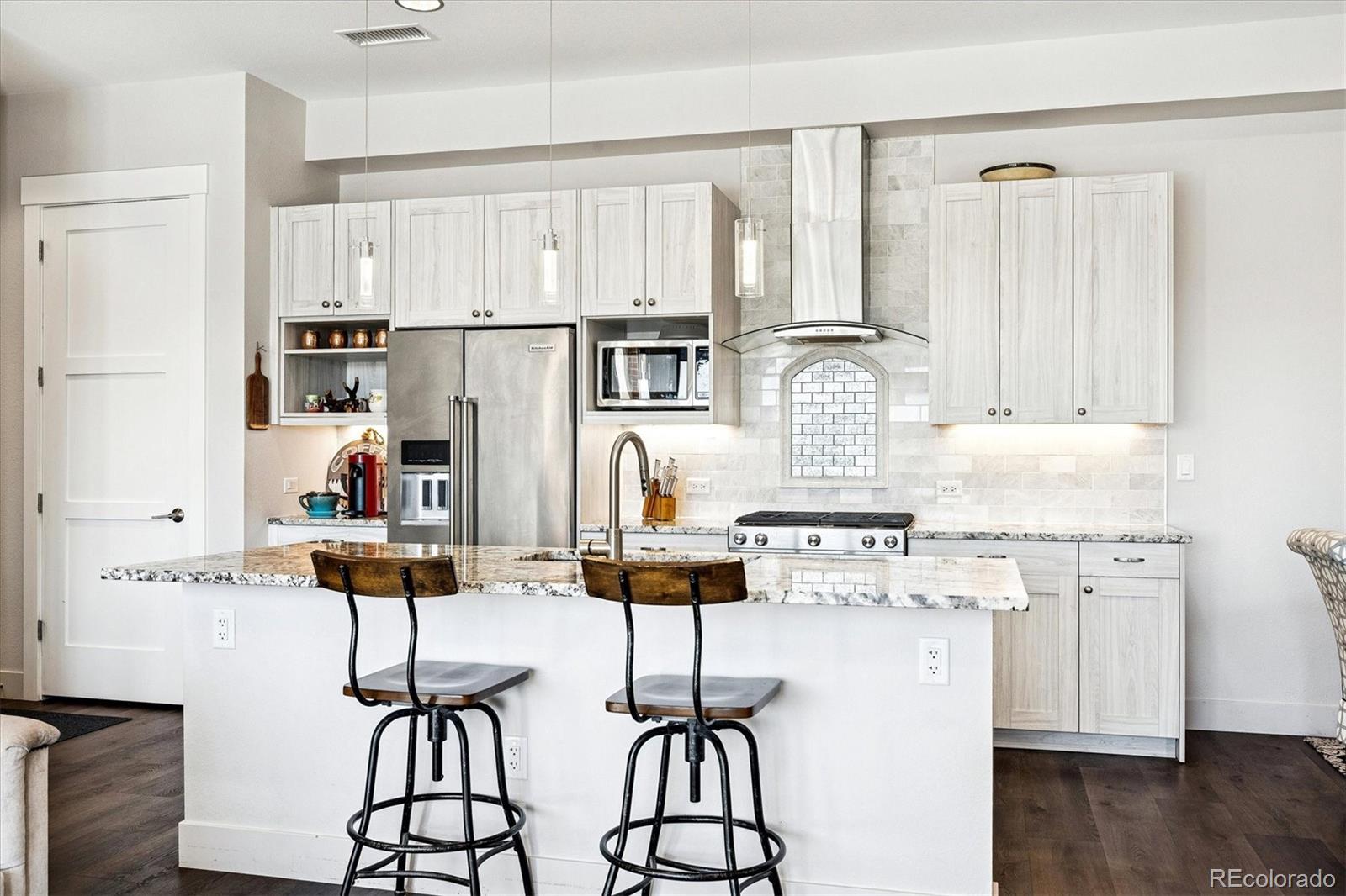 4885 South Monaco Street, Unit 207 Denver, CO 80237 - Photo 11 of 33 a kitchen with stainless steel appliances kitchen island wooden floors and white cabinets