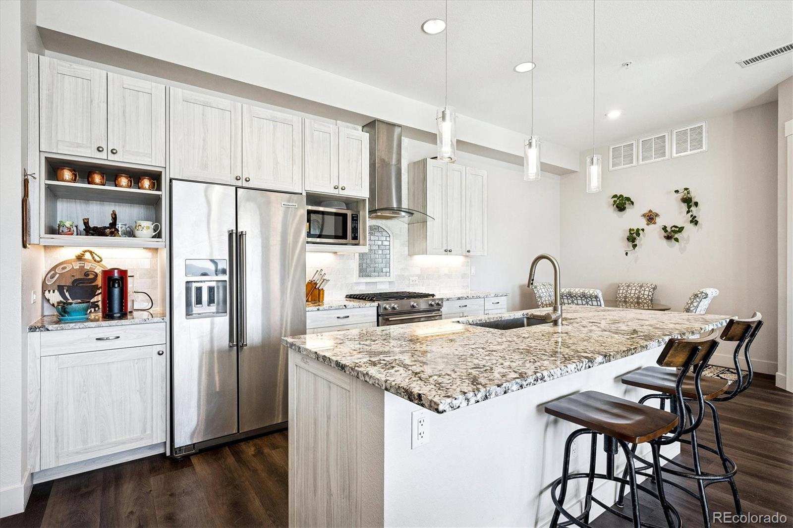 4885 South Monaco Street, Unit 207 Denver, CO 80237 - Photo 13 of 33 a kitchen with granite countertop a refrigerator a stove a sink and white cabinets with wooden floor