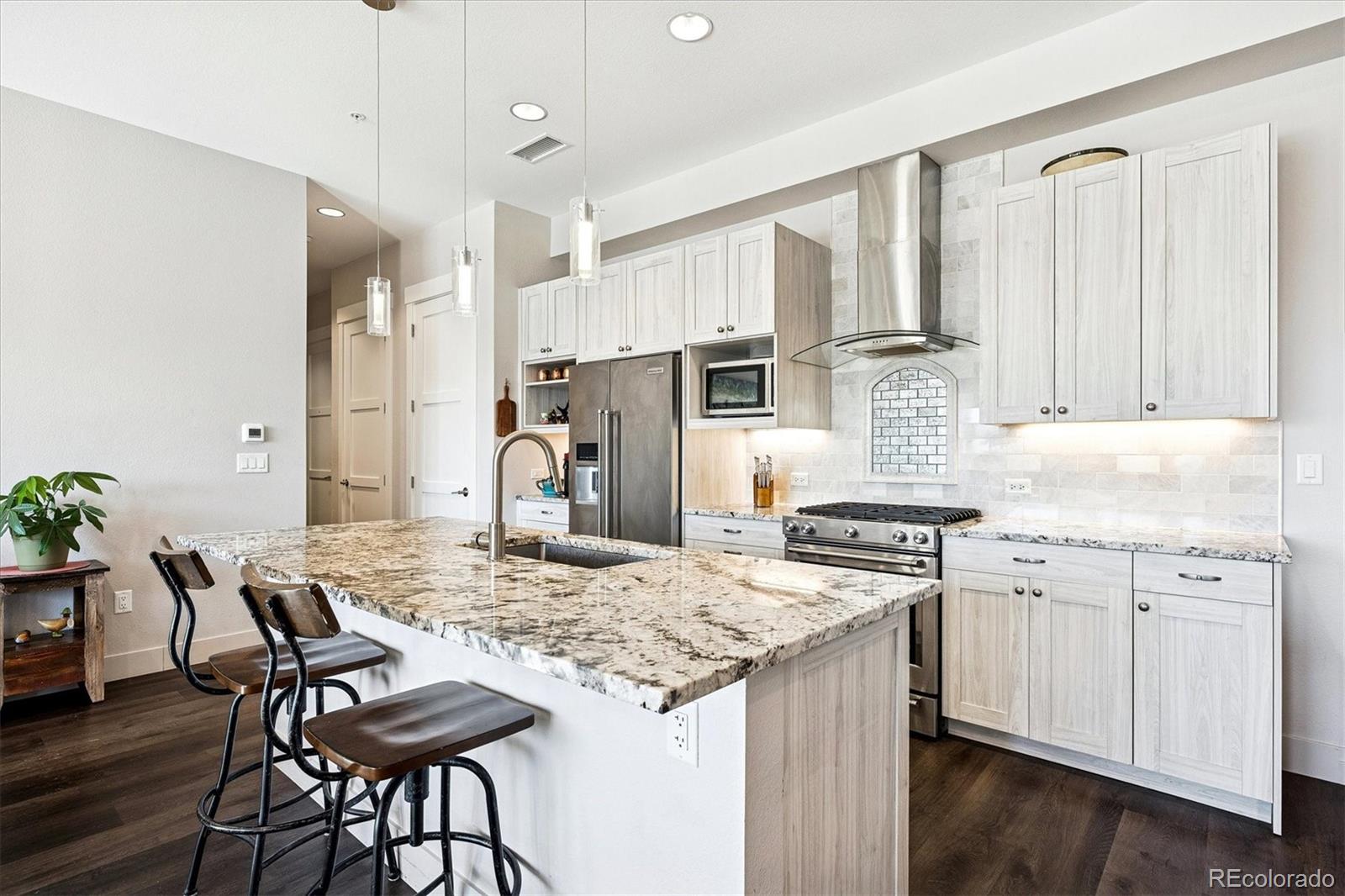 4885 South Monaco Street, Unit 207 Denver, CO 80237 - Photo 14 of 33 a kitchen with granite countertop white cabinets and stainless steel appliances