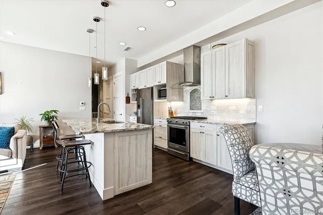 a kitchen with stainless steel appliances kitchen island granite countertop wooden floors and white cabinets