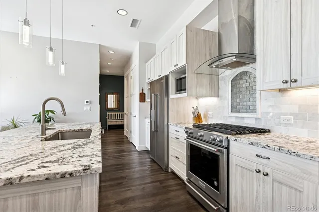 a kitchen with granite countertop a stove a sink and a refrigerator