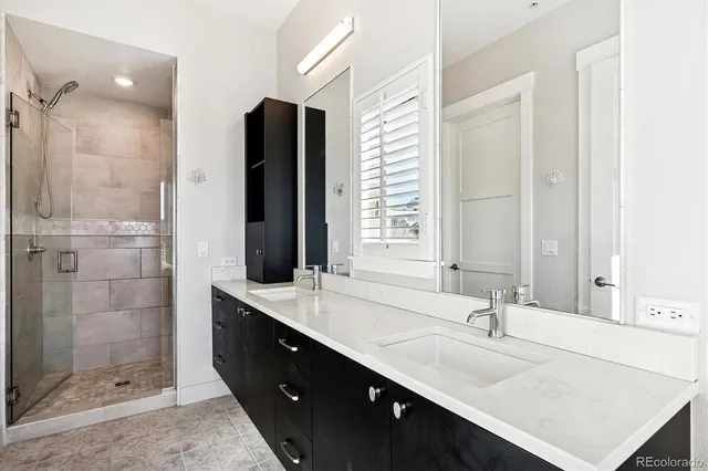 a bathroom with a double vanity sink mirror and shower