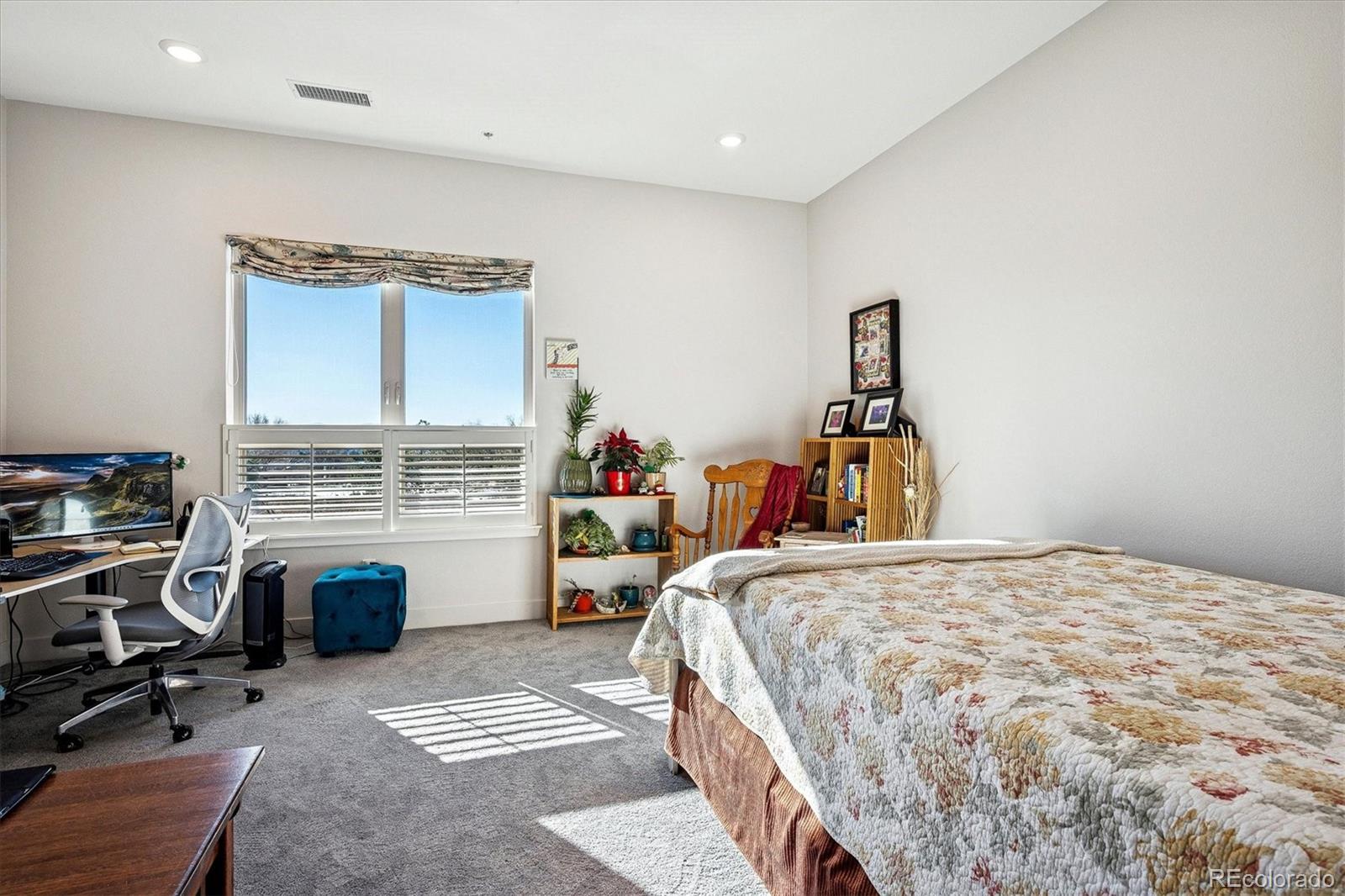 4885 South Monaco Street, Unit 207 Denver, CO 80237 - Photo 26 of 33 a bedroom with a bed a couch and a flat tv screen on the dresser