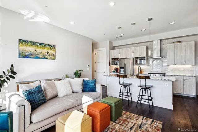 a living room with furniture kitchen view and a wooden floor
