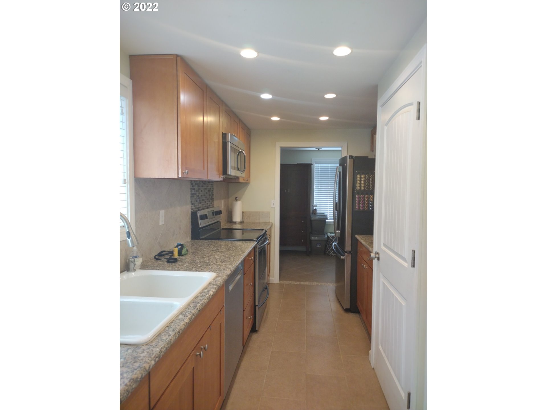18024 Southeast Marie Street Portland, OR 97236 - Photo 7 of 31 a kitchen with kitchen island sink and refrigerator