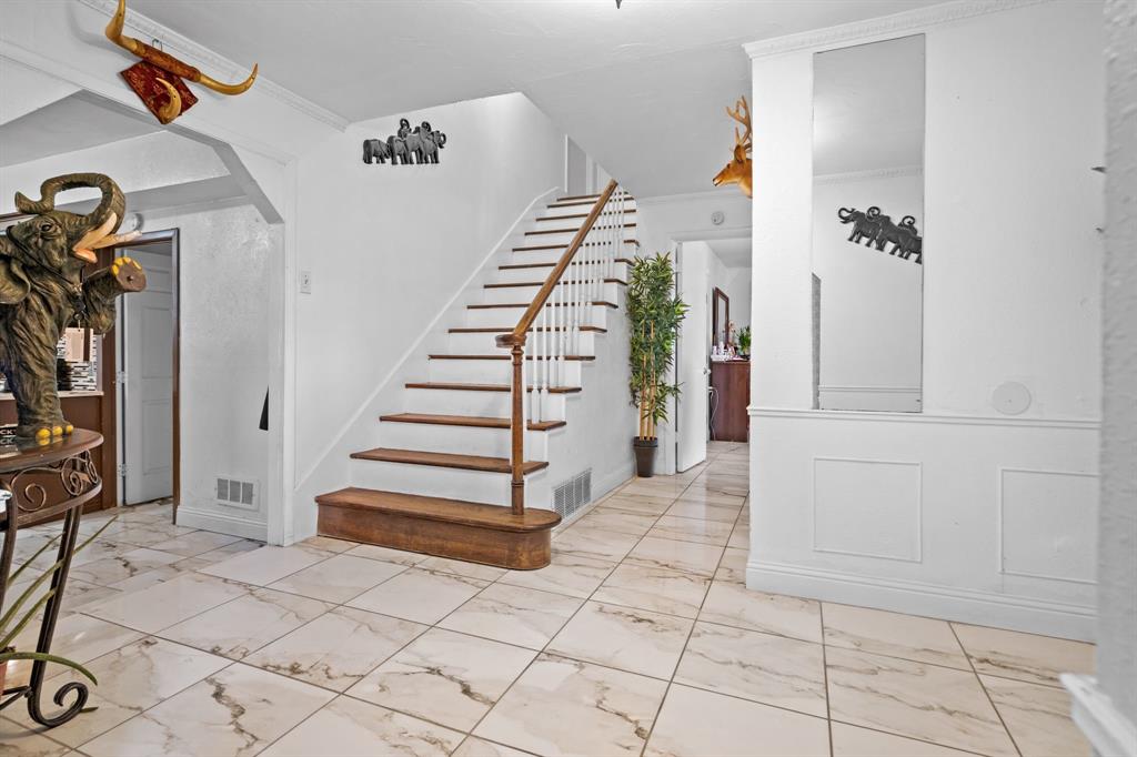 2133 Pleasant Drive Dallas, TX 75227 - Photo 17 of 40 Stairway with arched walkways, marble look tiles, and crown molding