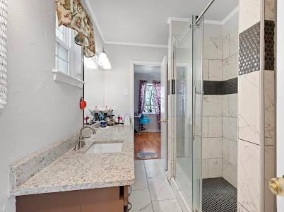 2133 Pleasant Drive Dallas, TX 75227 - Photo 20 of 40 Bathroom featuring a shower stall, vanity, crown molding, and light marble finish floors