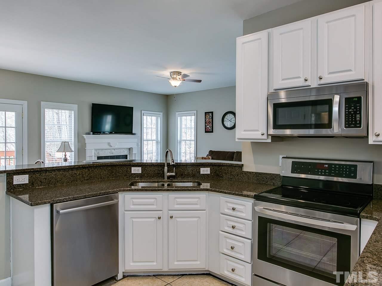 832 Kings Cross Way Raleigh, NC 27615 - Photo 3 of 25 a kitchen with granite countertop white cabinets and black appliances