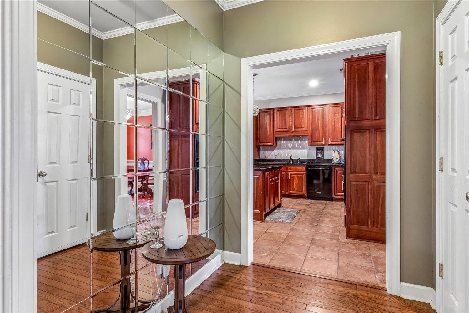 65 Summer Grove Road Memphis, TN 38018 - Photo 15 of 38 Hardwood flooring, crown molding, paneled interior doors, full-height wall mirror, and a kitchen featuring wood cabinetry and tile flooring