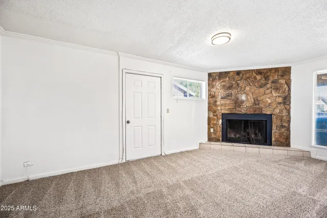 a view of an empty room with a fireplace and a window
