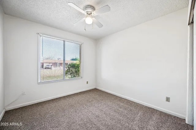 an empty room with a window and a fan