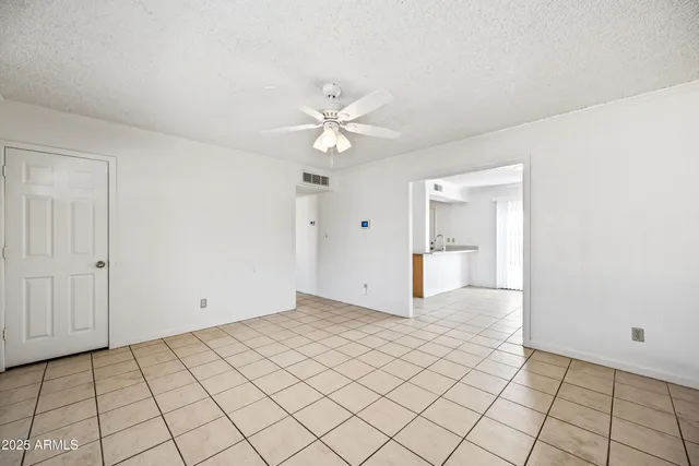 a view of an empty room and chandelier fan
