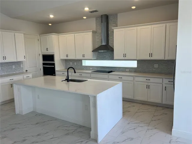 a kitchen with a sink white cabinets and a stove