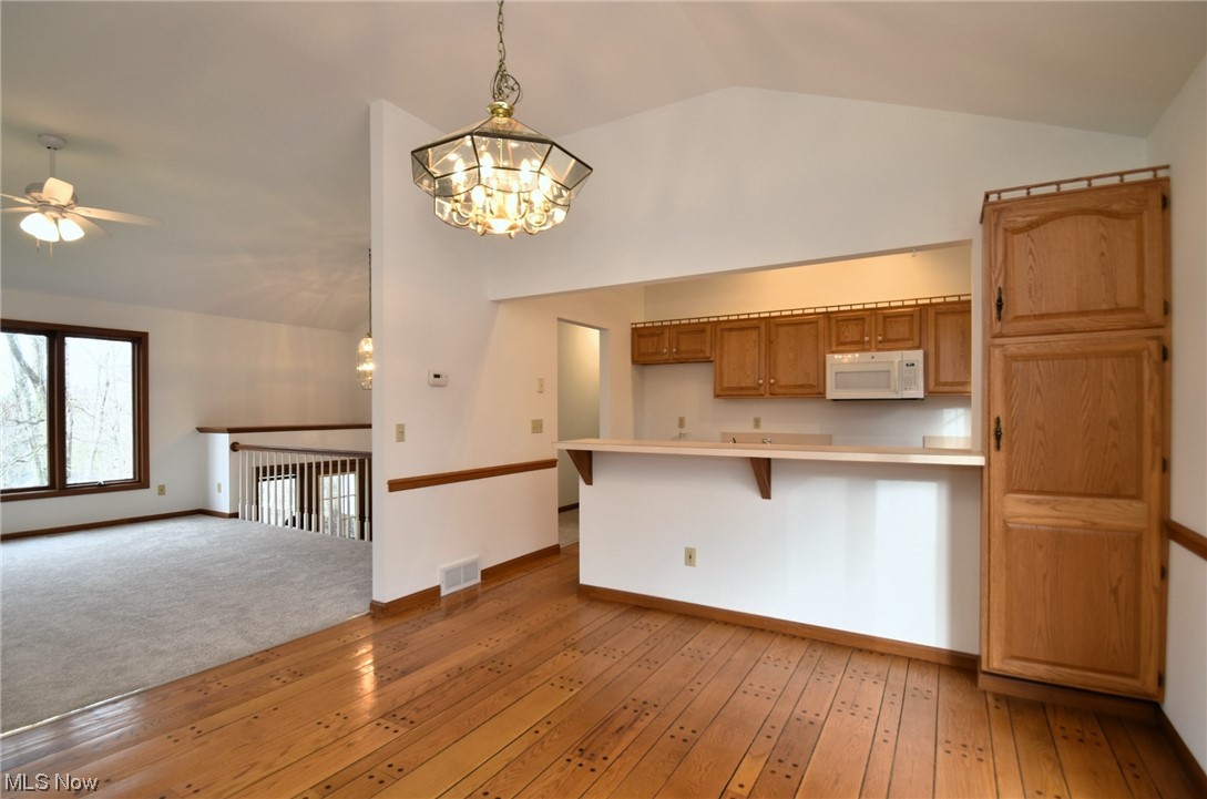 9699 Mulberry Road Chardon, OH 44024 - Photo 16 of 24 featuring pendant lighting, a breakfast bar, ceiling fan with notable chandelier, vaulted ceiling, and light hardwood / wood-style flooring