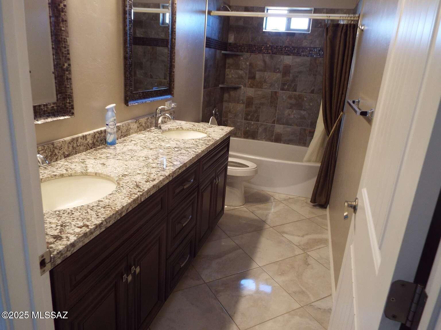 11553 East Tanque Verde Road Tucson, AZ 85749 - Photo 8 of 16 a bathroom with a granite countertop sink a mirror and shower