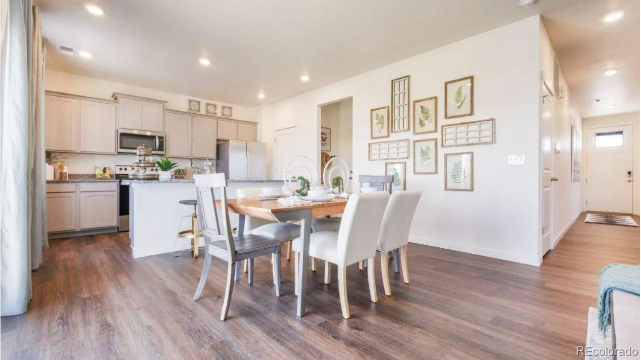 831 South Apex Avenue Fort Lupton, CO 80621 - Photo 5 of 18 a dining room with stainless steel appliances wooden floors a table and chairs