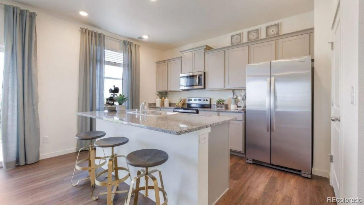 831 South Apex Avenue Fort Lupton, CO 80621 - Photo 6 of 18 a kitchen with stainless steel appliances granite countertop a refrigerator a stove and a wooden floors