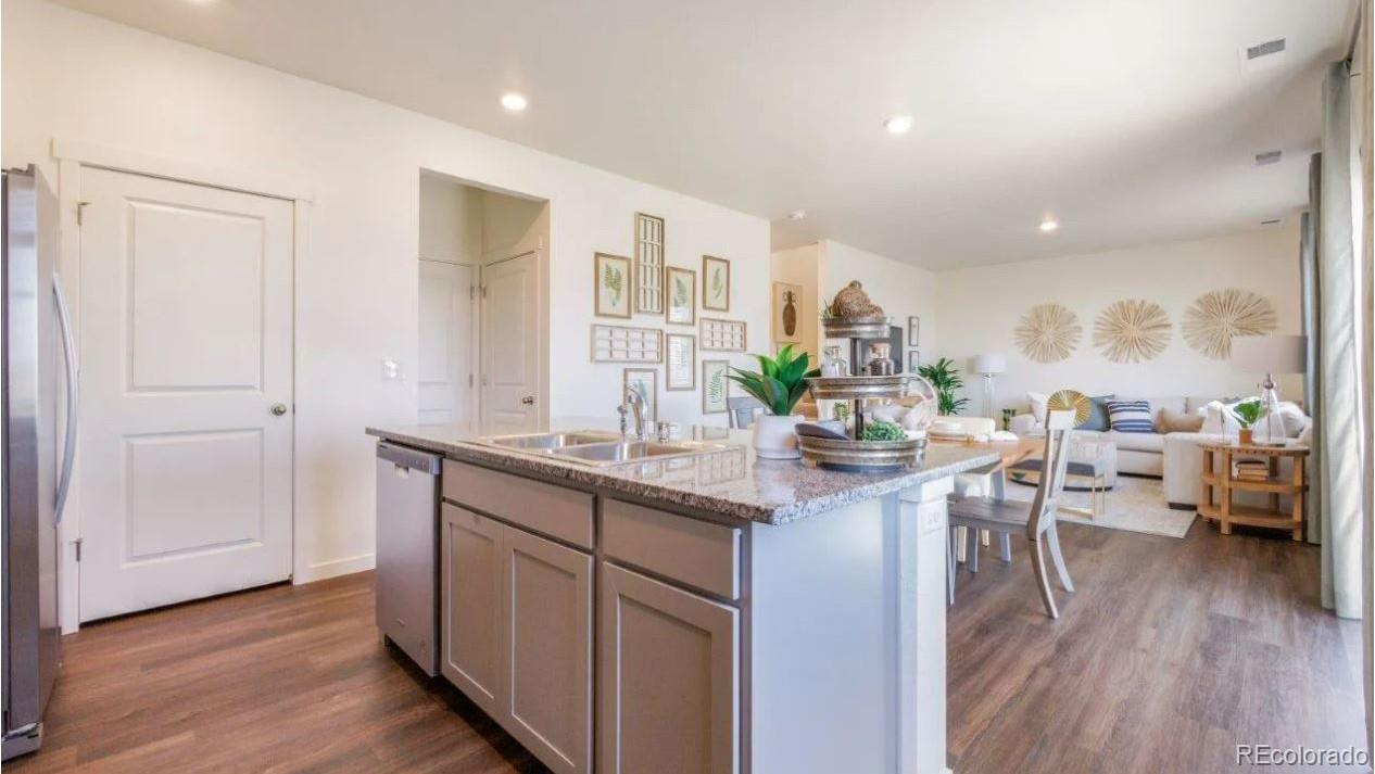831 South Apex Avenue Fort Lupton, CO 80621 - Photo 7 of 18 a kitchen with stainless steel appliances granite countertop a sink cabinets and wooden floor
