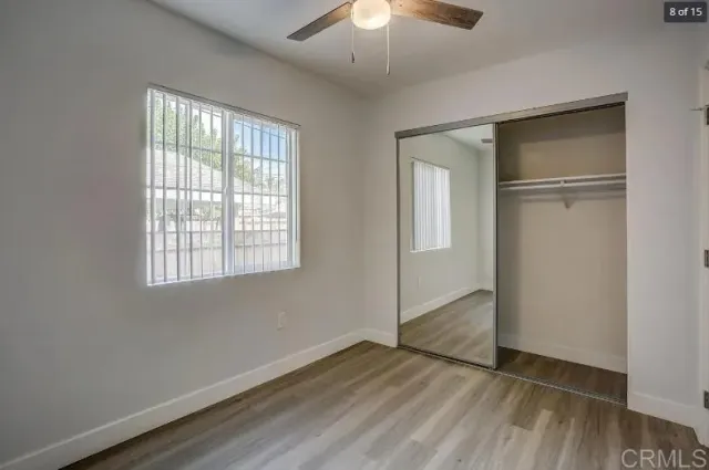an empty room with wooden floor cabinet and windows